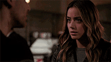 a woman in a leather jacket is looking at a man in a room .