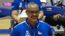 a man wearing glasses and a blue shirt that says ph1 on it