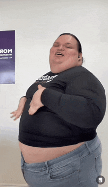 a woman with a very large belly is dancing in front of a poster that says rom