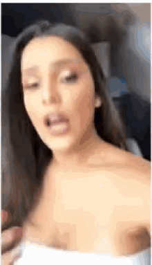 a woman with long hair is wearing a white top and talking .