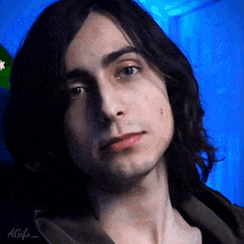 a close up of a man 's face with long hair and a blue background .