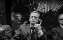 a man in a suit and tie is talking on a phone in front of a map of the world