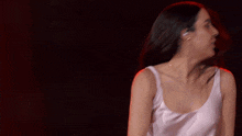 a woman in a white tank top is dancing and her hair is blowing in the wind