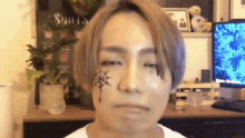 a man with a spider web on his face is making a funny face .
