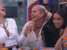three women are sitting at a table laughing together .