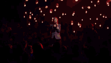 a woman singing into a microphone in a dark room