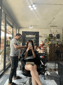 a woman sitting in a chair taking a picture of herself with her phone