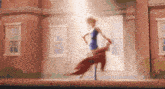 a woman in a blue dress and red cape is dancing in front of a building .