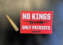 a red sign that says no kings only patriots is next to a bullet