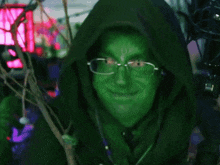 a person with green face paint and glasses is wearing a hood