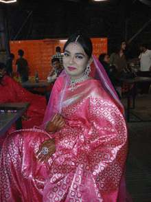 a woman in a pink dress sits in front of a sign that says ' the first access '