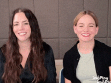 two women are sitting next to each other and smiling for a picture .