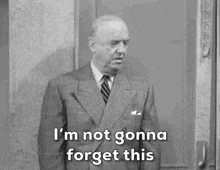 a man in a suit and tie is standing in front of a door and says i 'm not gonna forget this