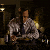 a man sits at a table with a plate of food and a bottle of wine with a label that says pinot grigio