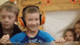 a boy wearing headphones is smiling in front of a group of kids