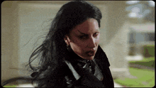a woman with black hair and red eyes is wearing a black leather jacket