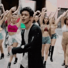 a group of people are dancing on a street with a man in the middle