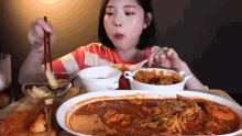 a woman is eating a large bowl of food with chopsticks .