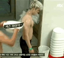 a man without a shirt is being showered by another man with a sign that says jtbc on it