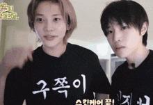 two young men are standing next to each other with one wearing a black shirt with chinese writing