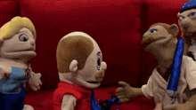 a group of puppets are sitting on a red couch talking to each other