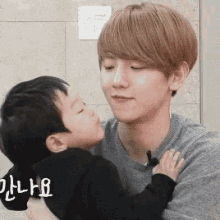 a young man is holding a small child in his arms and kissing him on the cheek .