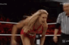 a woman in a bikini is standing in a wrestling ring