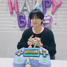 a man wearing a birthday hat is sitting in front of a cake that has the number 27 on it