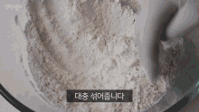 a person is mixing flour in a bowl with korean writing on the bottom