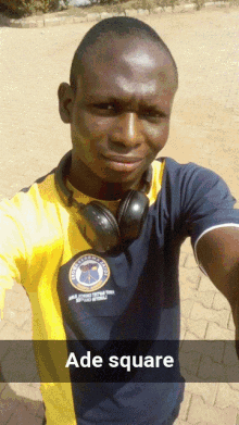 a man wearing headphones takes a selfie with the words ade square below him