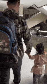 a little girl holds a man 's hand while walking down stairs