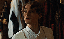 a man in a white shirt and suspenders is standing in front of a closet .