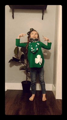 a little girl in a green sweater with a shamrock on it