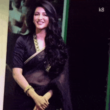 a woman in a black saree is standing in front of a sign that says k8 on it