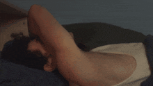 a person laying on a bed with their arm over their head .