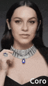a woman is wearing a necklace and a ring with a blue stone pendant .