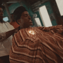 a man is getting his hair cut by a barber wearing a striped shirt