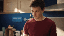 a man in a red shirt is standing in a kitchen with a sign that says " wind & salt " on it