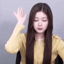 a woman with long hair is wearing a yellow shirt and making a face .