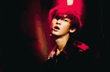 a man with red hair is singing into a microphone in a dark room