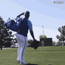 a baseball player carrying a duffel bag with kc on it