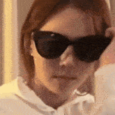 the woman is wearing sunglasses and a white shirt .