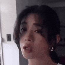 a close up of a woman 's face with a ponytail making a funny face .