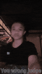 a girl in a black shirt says " you wrong judge " in a dark room