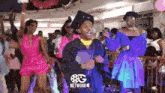 a man in a graduation cap and gown is dancing in a crowd with a network logo