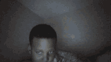 a person is laying in a dark room with a striped blanket