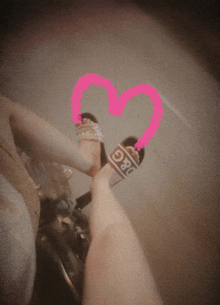 a person wearing a pair of d & g sandals with a pink heart in the background