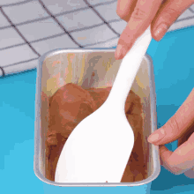 a person is using a white spatula to stir a chocolate sauce