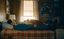 a man laying on a bed with a dog and a poster that says mighty charloys