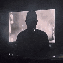 a silhouette of a man wearing headphones stands in front of a screen
